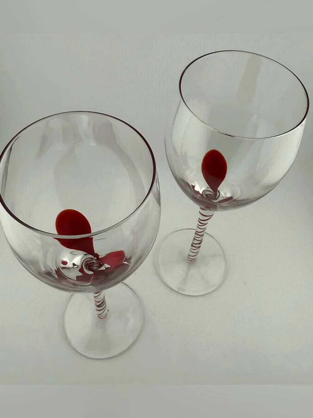 2 Pier 1, red ribbon swirl stem wine glasses, w/ a red swirl design on the stem.